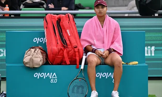a person sitting on a bench with a tennis racket and a bag